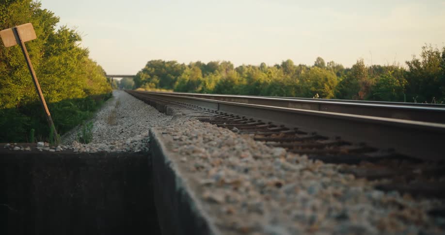 Railway track close to a bridge surrounded by trees outdoors during day time