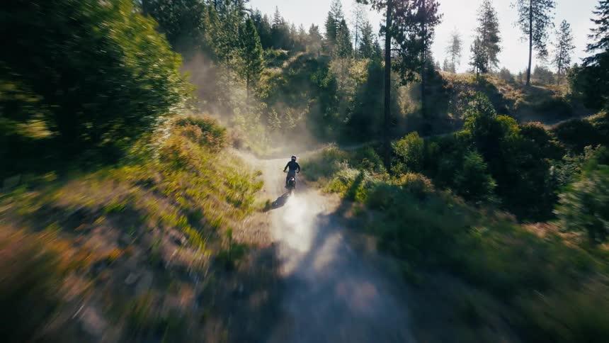 The dirt bike races up the hill leaving a dust cloud
