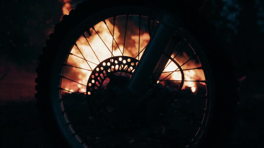 Bicycle wheel next to a bonfire surrounded by trees outdoors during night time
