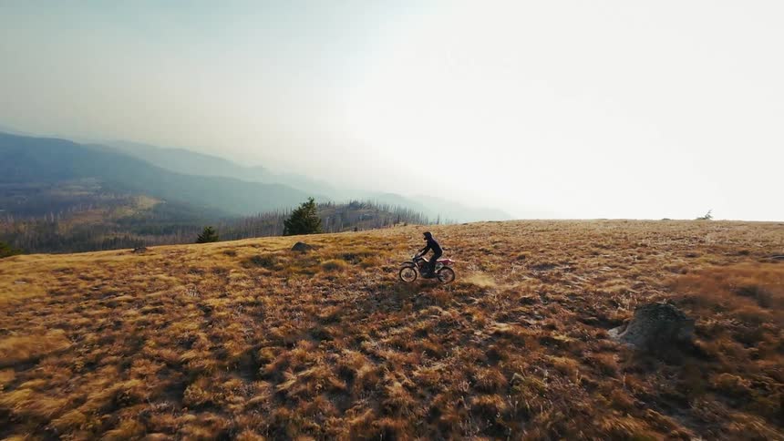 The dirt bike races on the large hill on a foggy day