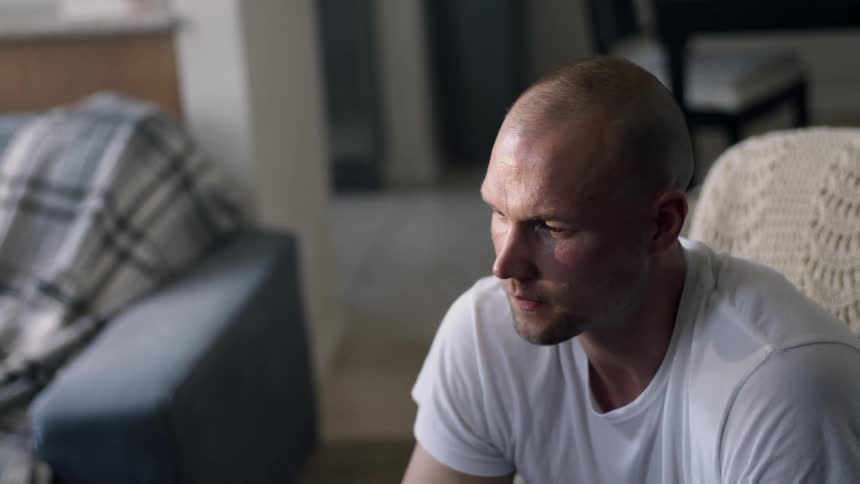 A man sits in a chair and shakes his head