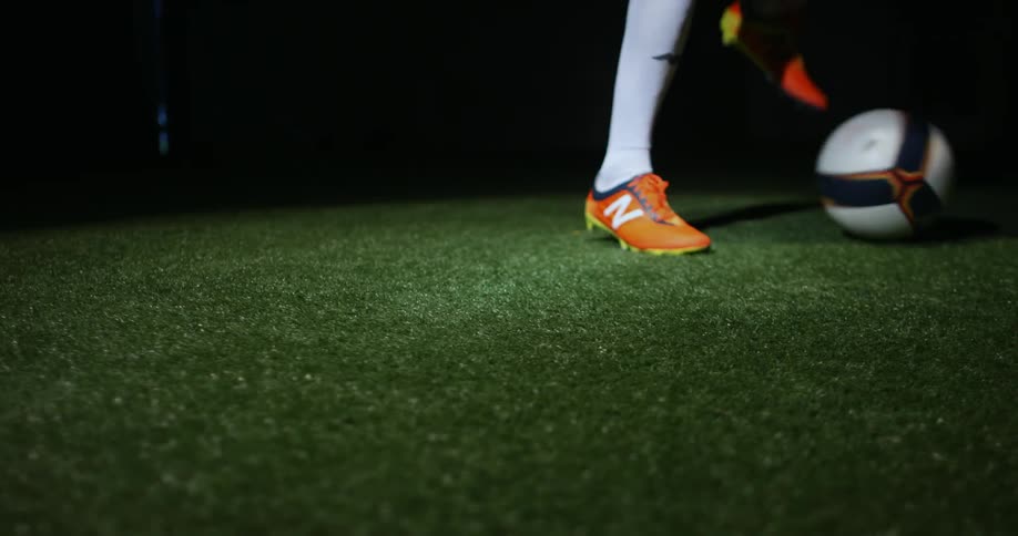 A person is kicking a soccer ball in the dark