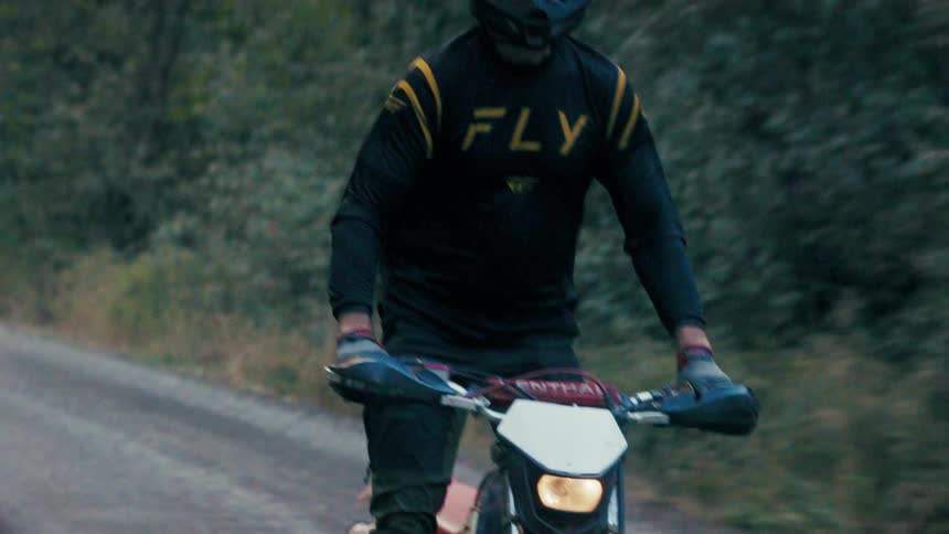 The man stands on his dirt bike as he rides