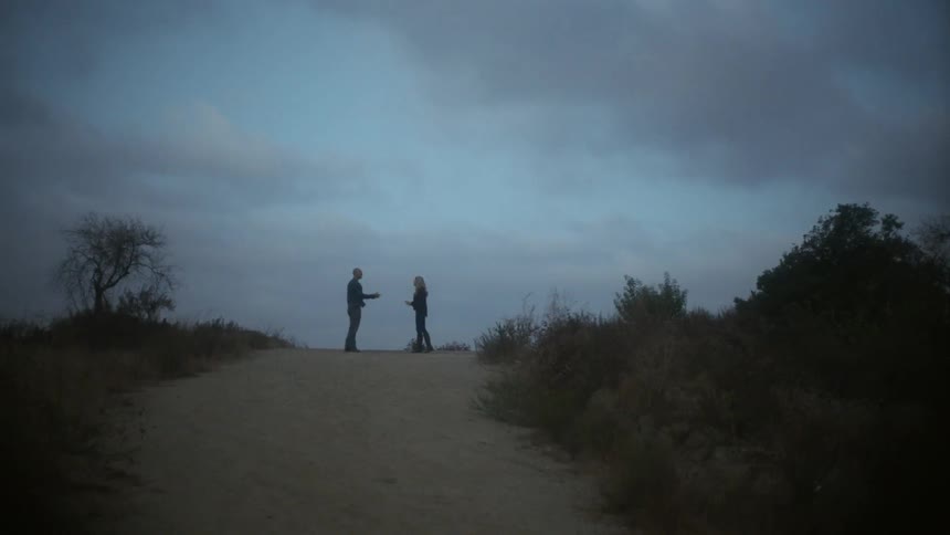 A man and woman argue outside on a cloudy day