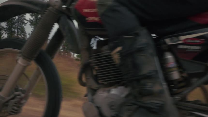 Front detail of a motocross motorcycle in motion on a dirt trail with a blurred background