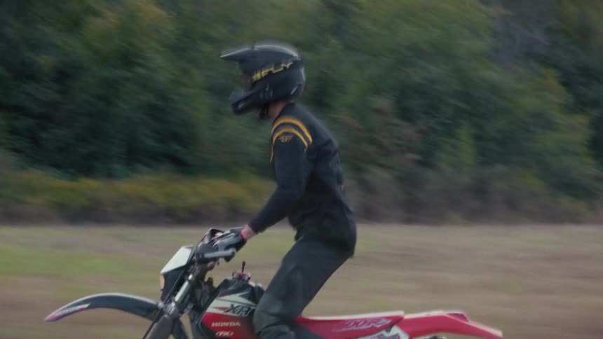Motocross rider riding at high speed across open terrain with a blurred background