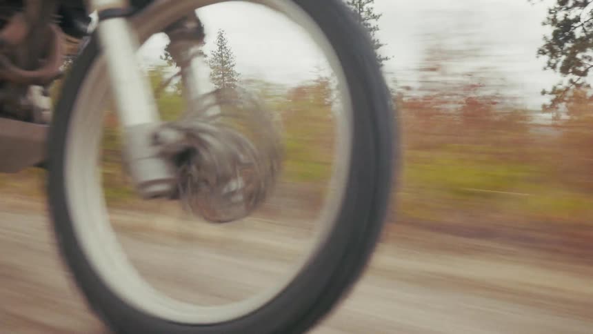Front wheel of motorcycle in motion on dirt trail with visible suspension
