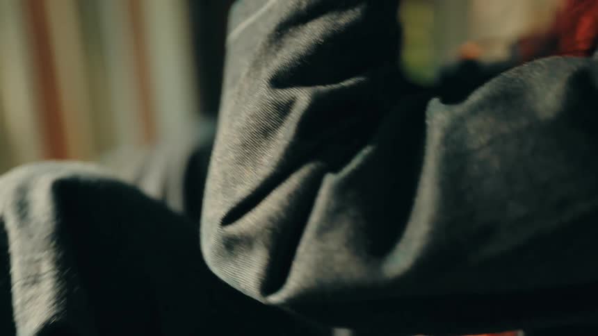 Arm resting on a knee with natural light falling on dark fabric in an indoor setting