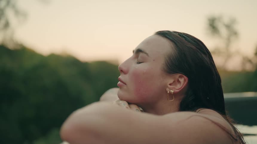 Woman resting on their arms while looking at an outdoor landscape at sunset