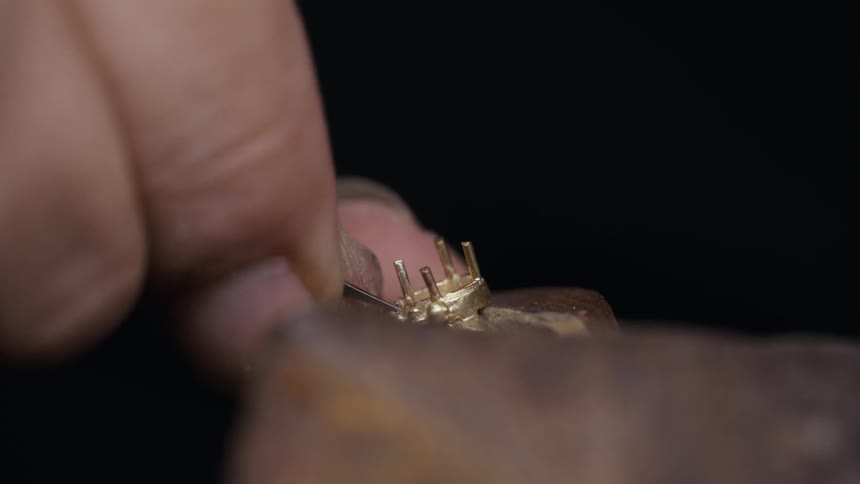 Closeup hands of a jeweler working on a jewelry with a bud bur tool