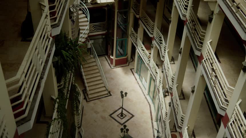The man walks down the stairs towards the hotel lobby