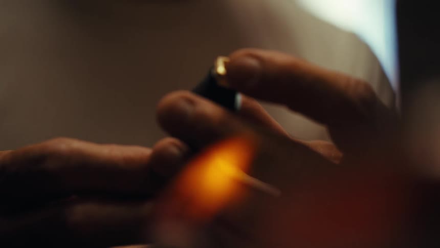 Hands holding a small cylindrical object with an outoffocus amber light in the foreground