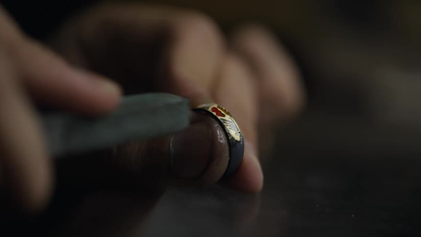 Closeup hands of a jeweler filing a ring with a tool