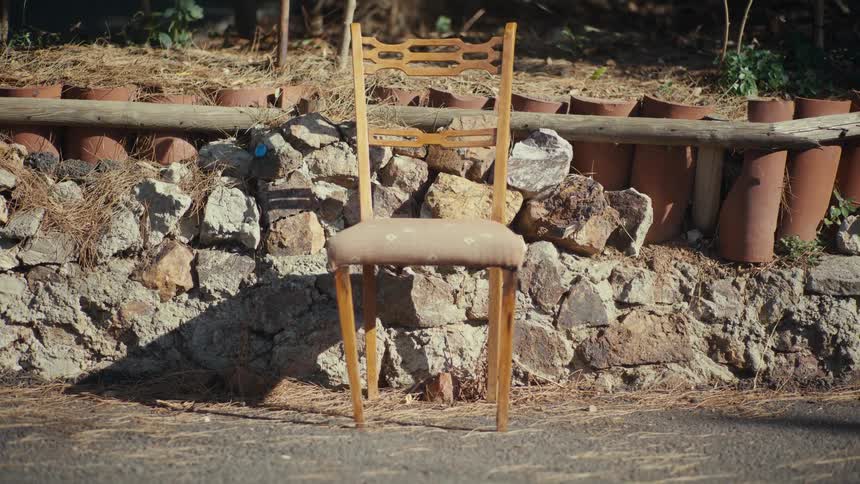 Wooden chair placed in front of a stone wall in an outdoor area