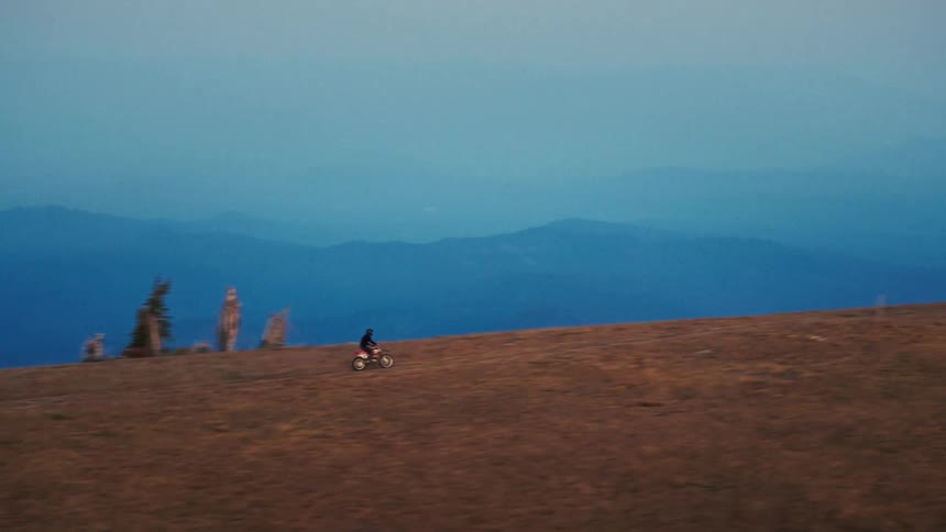 The dirt bike races past the watch tower on the mountain