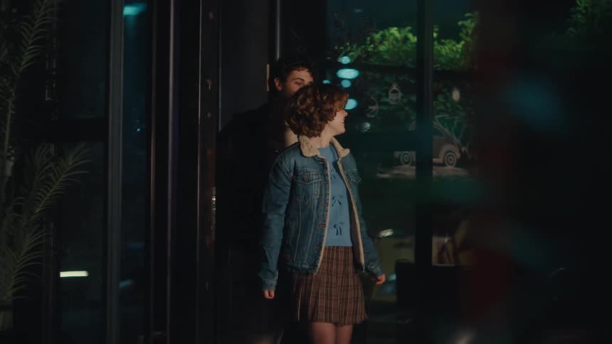 People walk on the sidewalk in front of a building as others walk out of revolving doors