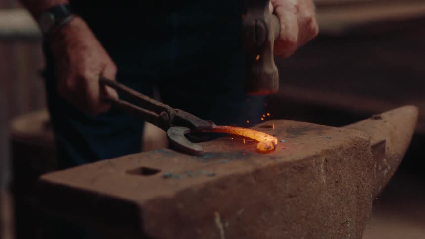 The blacksmith is hammering tongs on the anvil