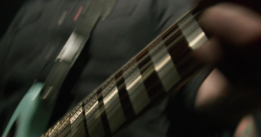 Musicians hand playing an electric guitar with motion blur in closeup under low lighting