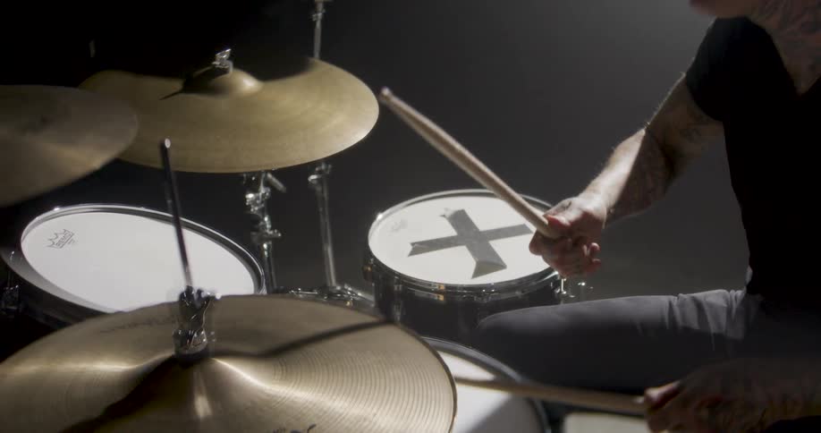 Man with multiple tattoos plays the drums