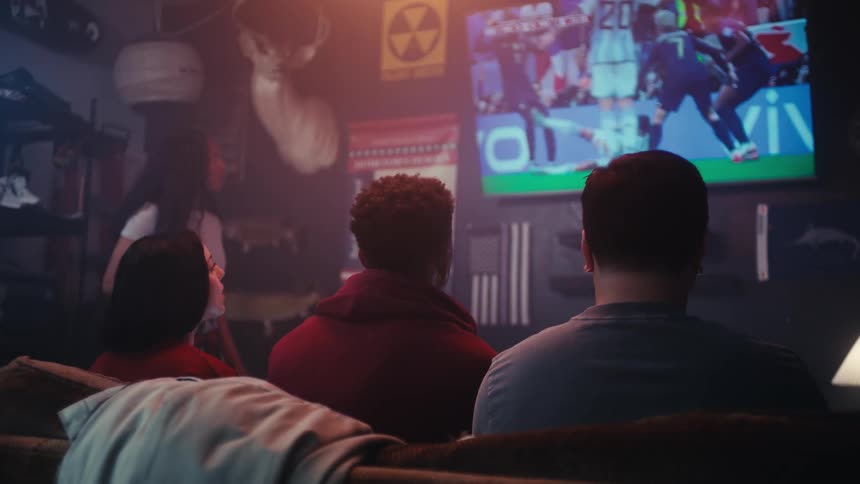 Four adults are watching a soccer game on television