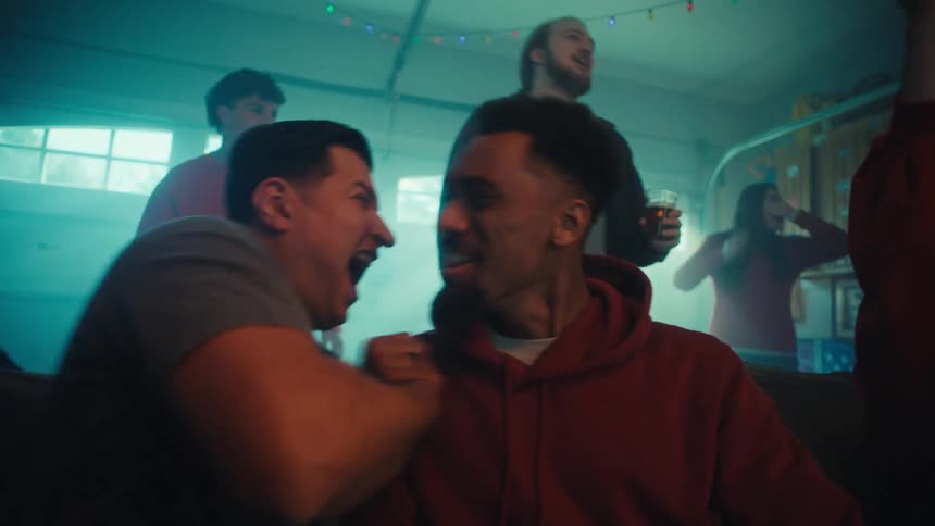 Group of friends smiling and cheering while they watch sports indoors during day time