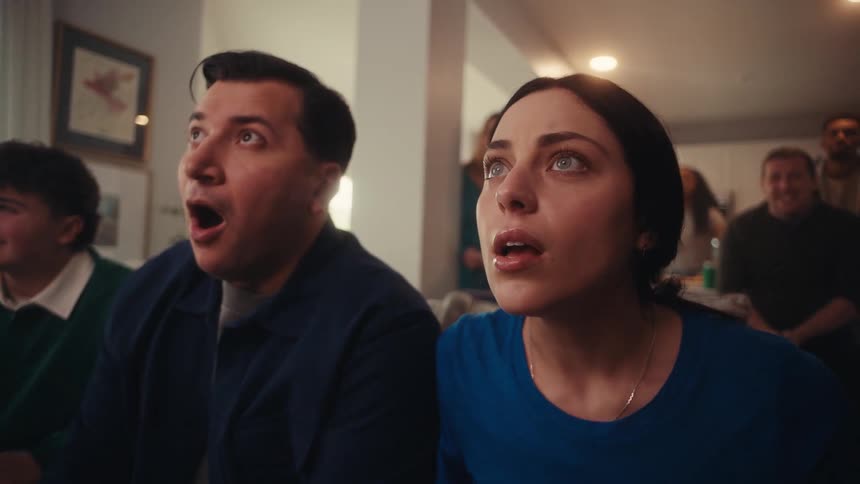 People in a house having a party and watching television cheer in excitement