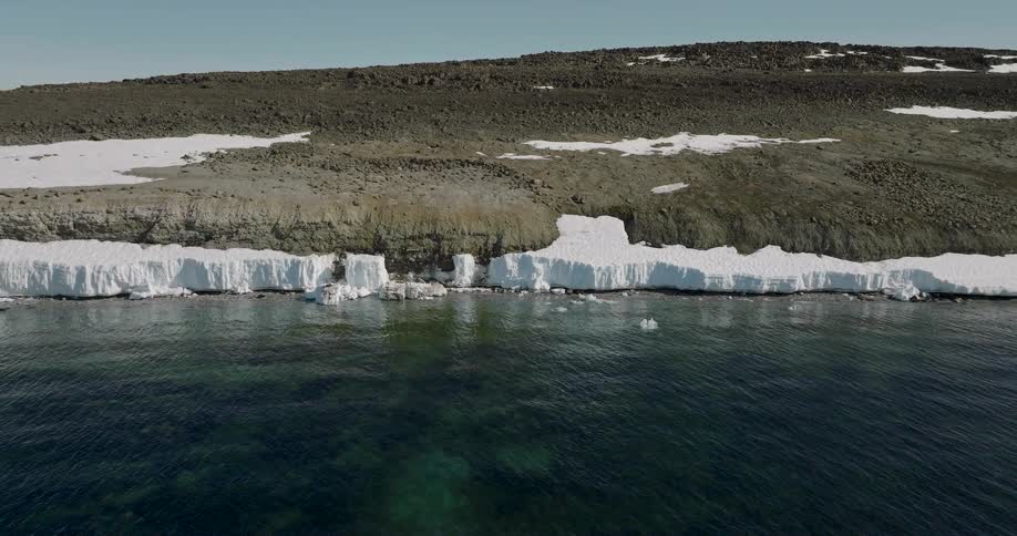 Coastline with a rocky cliff and an ice shelf bordering dark waters