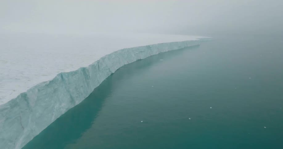 Ice shelf extends over cold waters beneath dense fog