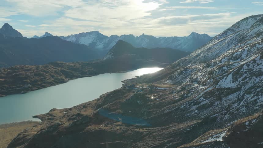 An aerial view of a landscape with a lake and snow covered mountains