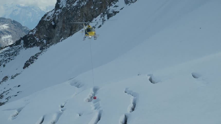 A helicopter flying over a snowy mountain area