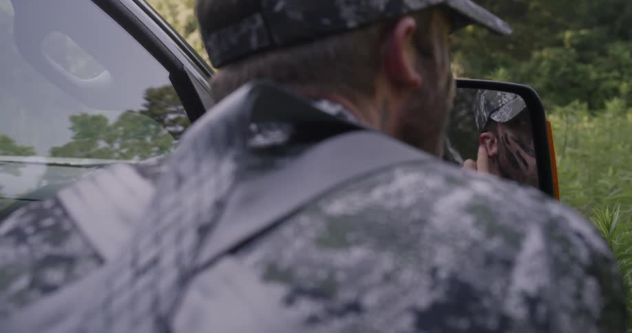 A man dressed in camo applies face paint