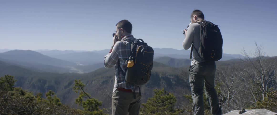 Hikers take pictures while standing in the mountains