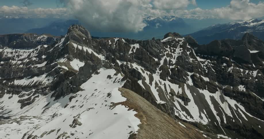 A vast snow dusted mountain range stretches across the horizon under a cloudy sky