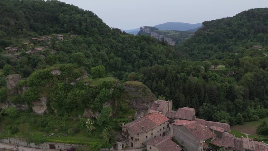 Aerial view of a rural village with terracottaroofed houses surrounded by wooded hills