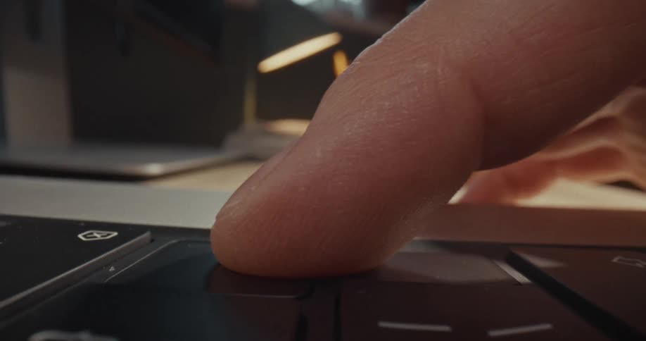 A finger pressing a key on a laptop keyboard