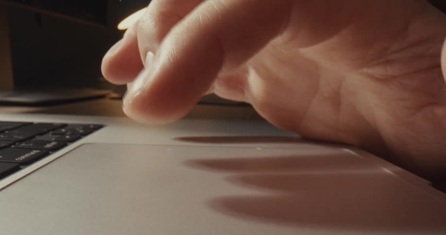 Finger touching a laptop trackpad on a work desk