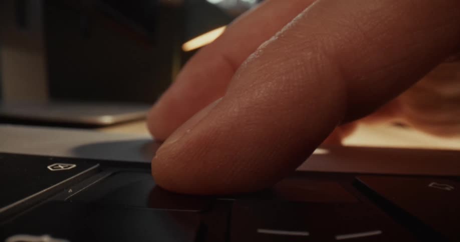 Finger presses a keyboard key in closeup under warm lighting