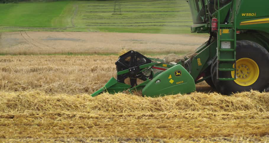 Agricultural harvester operating in a dry grain field with cutting equipment collecting straw