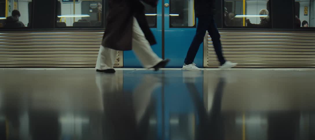 Passengers walking along the platform in front of a train stopped at a station