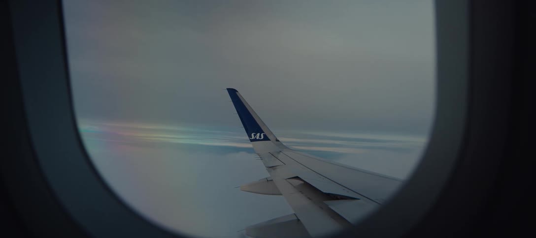 Airplane wing visible through the window during flight above the clouds