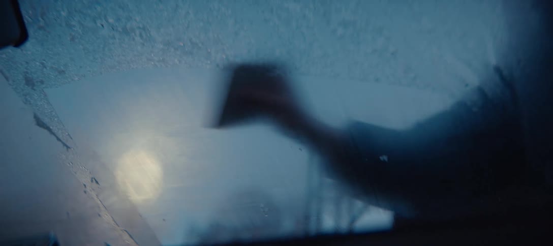 Person removing ice from a frozen surface with a scraper