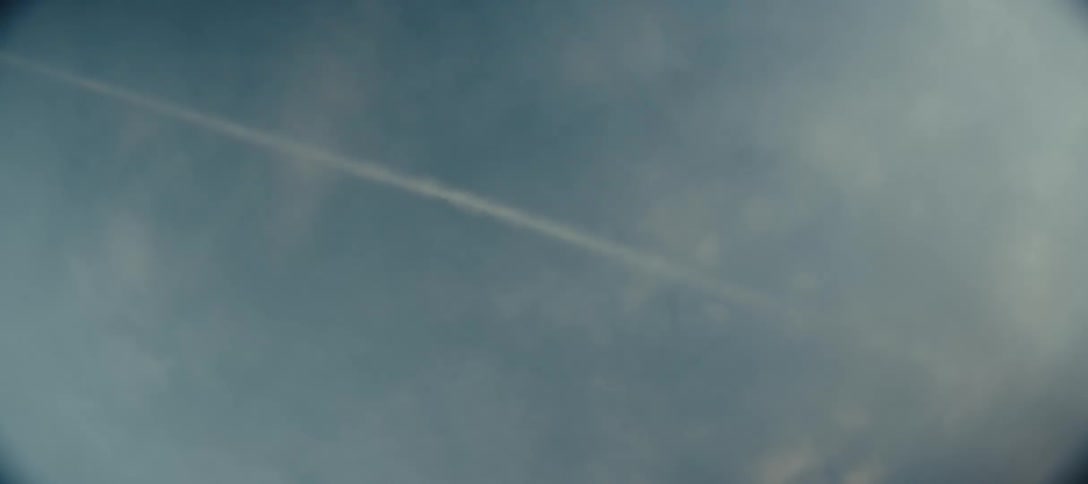 Contrail stretches across the partly cloudy sky