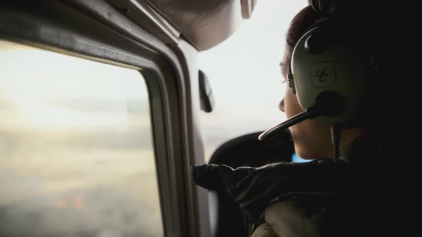 A female pilot wearing a headset gazes out of the cockpit window during a flight the scene captures her profile in soft natural light as the aircraft travels through the sky