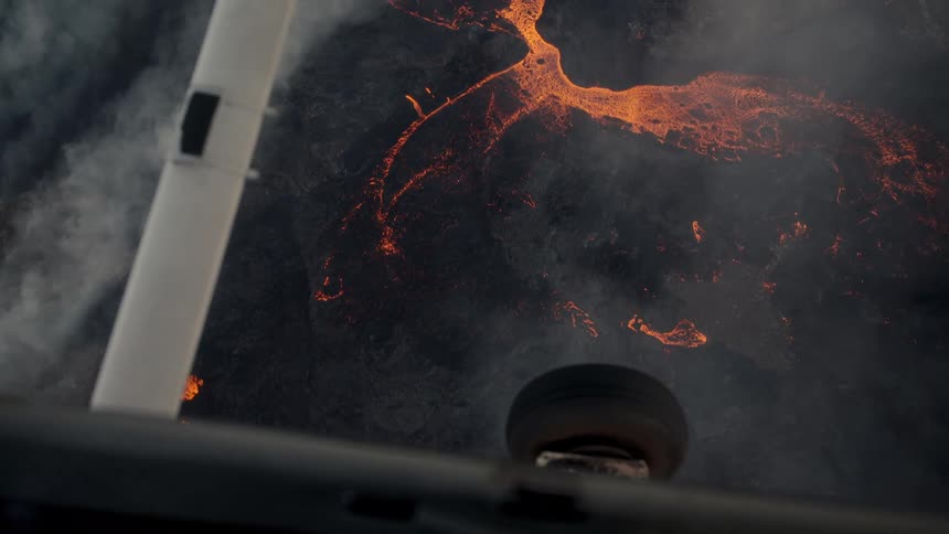 A plane flying over a mountain with lava