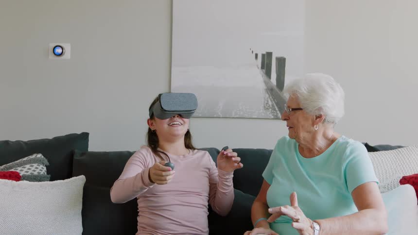 An older woman watches a girl use virtual reality