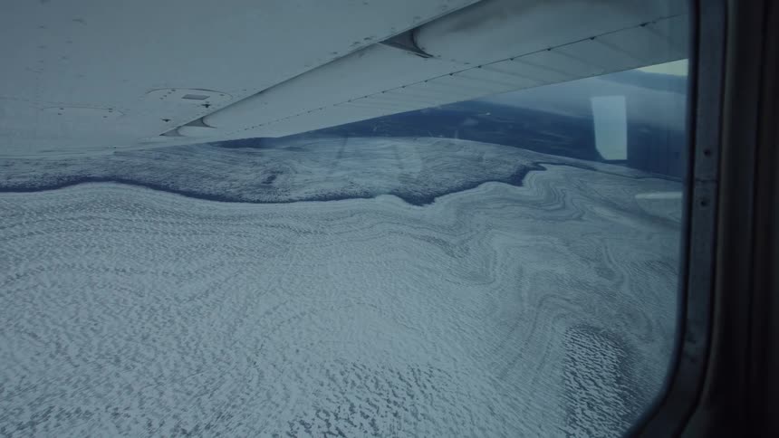 View from an airplane window in full flight over natural areas covered in snow