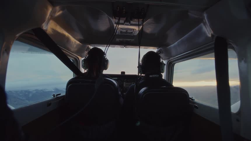 Pilots operate aircraft in flight over mountains at dusk