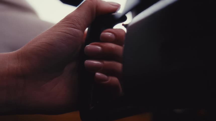 A close view shows the hand of a woman with pink nails firmly gripping the control wheel inside an airplane cockpit during a flight