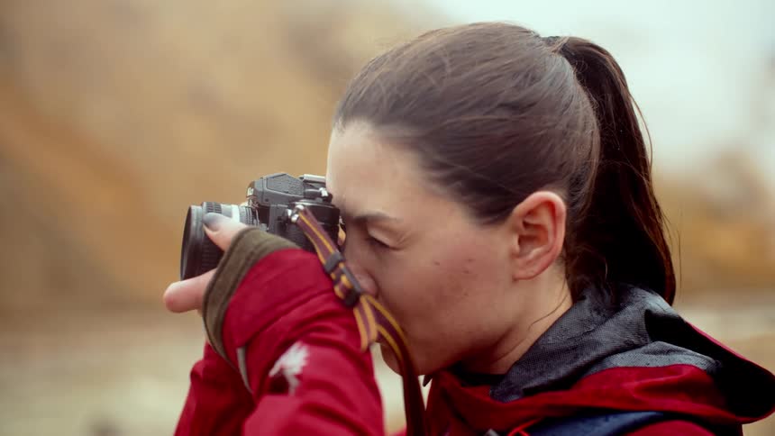 Woman in a volcanic mountain area taking photographs with a professional camera