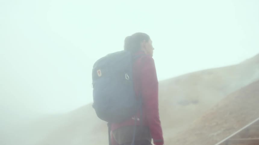 Female backpacker climbs the steps on a slope on a foggy autumn day